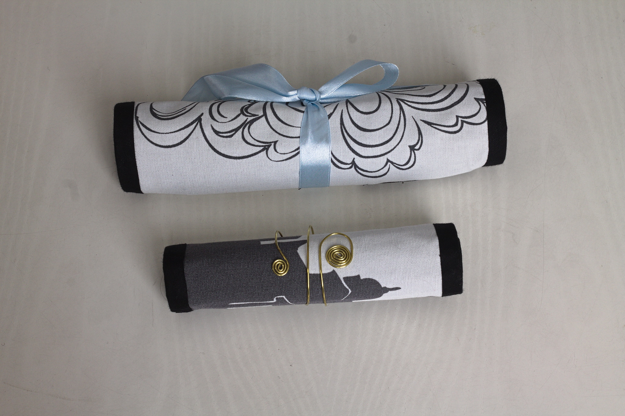 Picture of two fabric rolls, one closed with a ribbon, the other one with a metal ring.